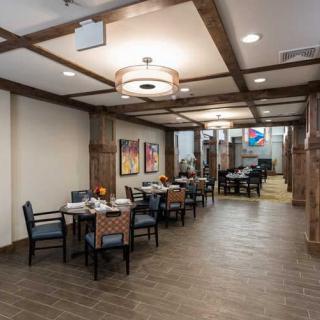 A cozy dining area with tables and chairs, featuring wooden beams and decorative artwork on the walls.