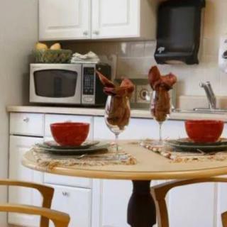 A neatly set dining table in a kitchen with wine glasses, red bowls, and napkins.