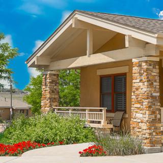 A charming house with a welcoming porch and beautiful landscaping under a clear blue sky.