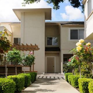 A charming residential building with a well-maintained garden and walkway.