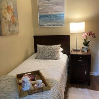 A cozy bedroom with a single bed, nightstand, and decorative artwork.