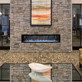 A modern living room with a stone wall fireplace and abstract artwork.