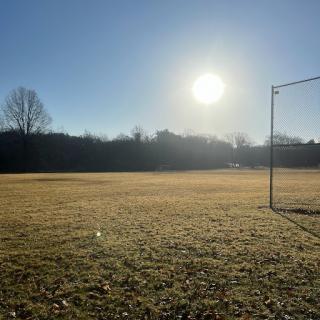 A serene soccer field basking in the sunlight on a clear winter morning.