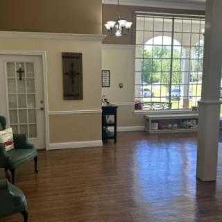 A spacious waiting area with large windows, comfortable seating, and wooden flooring.