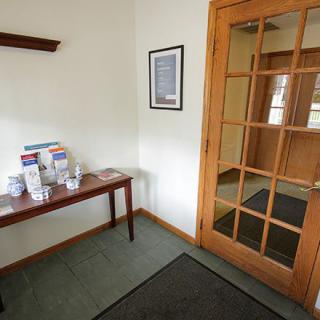 A small waiting area with brochures on a table next to a wooden door.