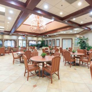A spacious dining area with wooden tables and chairs, featuring a chandelier and decorative wood beams.