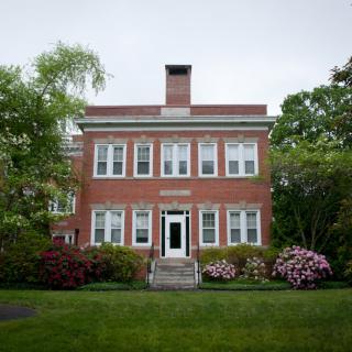 A brick house with a well-maintained front yard and surrounding greenery.