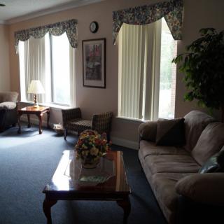 A cozy living room with sofas, a coffee table, and a lamp by the windows.