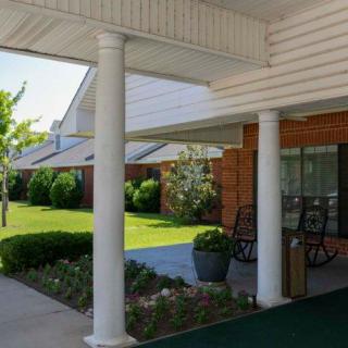 A welcoming porch with columns and a landscaped garden in front of a building.