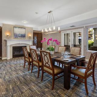 A well-appointed dining room with a large wooden table, surrounded by upholstered chairs, featuring a chandelier and a fireplace.