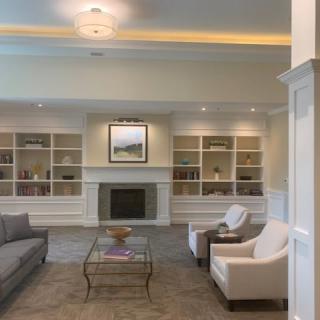A cozy living room with a fireplace, bookshelves, and comfortable seating arrangements.