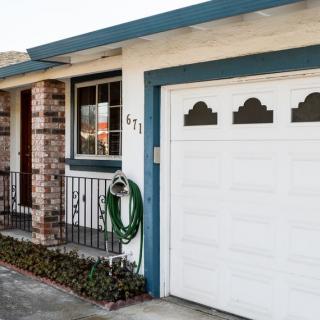 Front view of a house with a garage and garden hose coiled on the side.