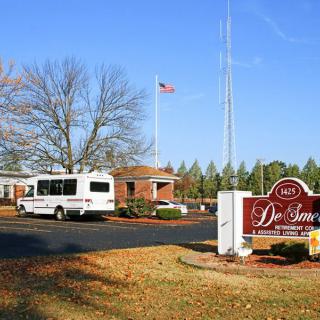 A building with a vehicle parked nearby, a flag flying, and a sign in the foreground.