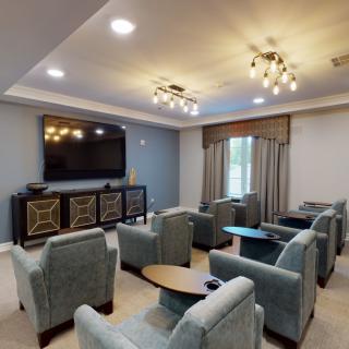 A cozy home theater room with plush seating and modern lighting, centered around a large television.