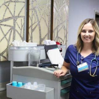 A nurse standing beside medical equipment in a healthcare setting.