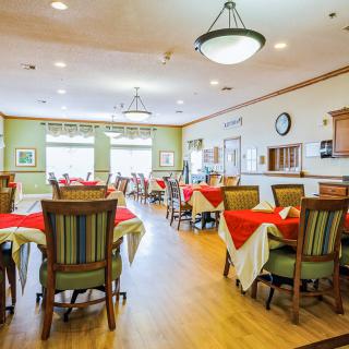 A brightly lit dining room with colorful table settings and empty chairs.