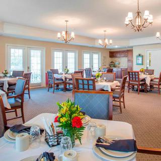 An elegant dining room with beautifully set tables, floral centerpieces, and chandeliers.