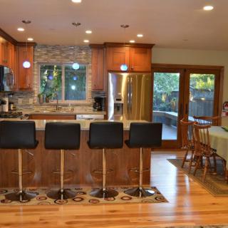 A modern kitchen with an island, bar stools, and a dining area.