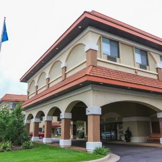 Exterior view of a hotel entrance with an arch design and flag displayed outside.