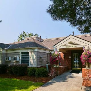 A charming residential building with a landscaped entrance featuring flowers and trees.
