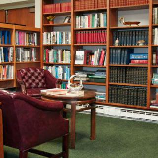 A cozy library corner with comfortable armchairs and bookshelves filled with books.