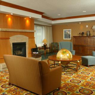 A cozy living room with a fireplace, comfortable seating, and patterned carpet.