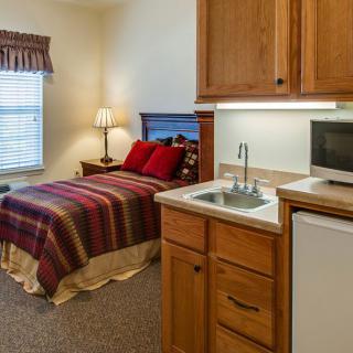 A cozy studio apartment with a bed, kitchenette, and warm decor.