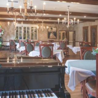 Elegant dining room with chandeliers and a grand piano.