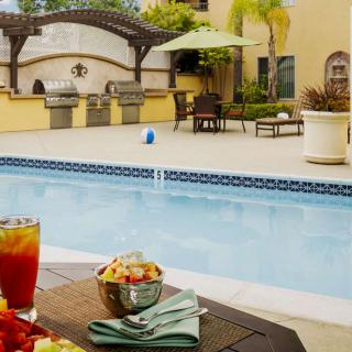 A serene outdoor patio with a swimming pool, table setting, and lounge area.
