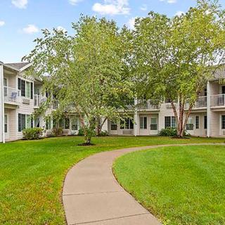 A peaceful apartment complex featuring a green courtyard with a winding pathway.