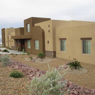 A modern southwestern-style stucco house surrounded by desert landscaping.