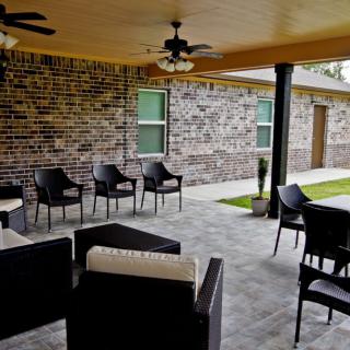 A cozy outdoor patio with comfortable seating and ceiling fans, perfect for relaxing.