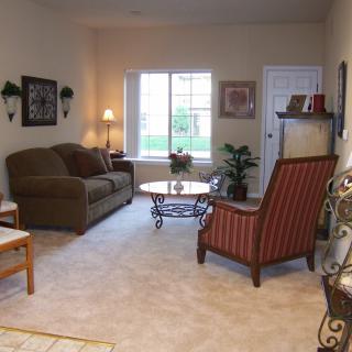 A cozy living room with a sofa, armchair, and a coffee table near a window.