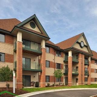 A modern apartment building with brick and siding exterior, featuring balconies and a gabled roof.