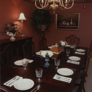 A formal dining room with an elegantly set table and a chandelier overhead.