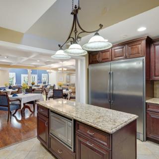 A modern kitchen featuring a granite countertop on the island, stainless steel appliances, and elegant chandelier lighting.