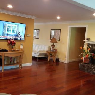 A cozy living room with wooden floors, a TV mounted on the wall, and elegant decor.