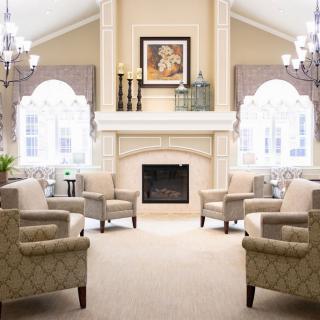 A luxurious living room featuring a central fireplace, surrounded by elegant armchairs and illuminated by grand chandeliers.