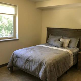 A cozy bedroom with a neatly made bed and a large window.