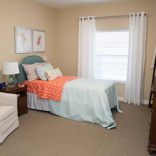 A cozy bedroom with a neatly made bed, colorful bedding, and simple decor.