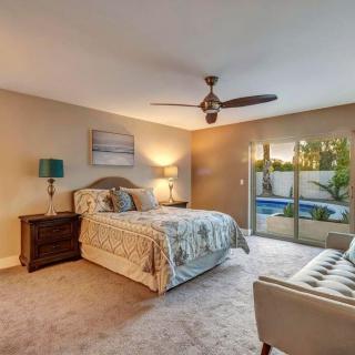 A modern bedroom with a comfortable bed, nightstands, and large windows offering natural light.