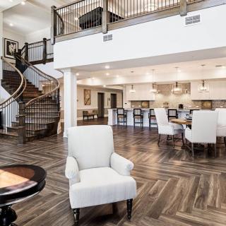 A spacious and modern open-concept living area with a view of the kitchen and an elegant staircase.