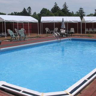 An outdoor swimming pool surrounded by chairs and tents.