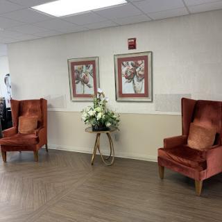 A cozy waiting area featuring two orange armchairs and decorative artwork on the walls.