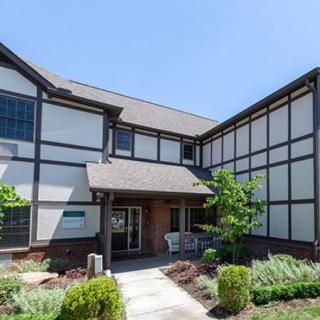 A two-story residential building with a Tudor-style exterior and landscaped front yard.