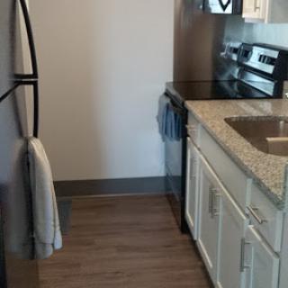 A modern kitchen featuring essential appliances, granite countertops, and wooden flooring.