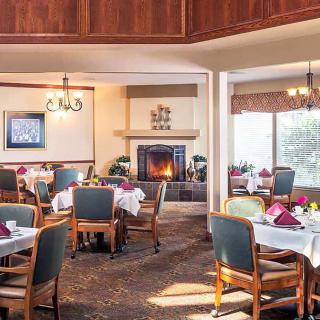 A cozy restaurant dining area featuring neatly set tables and a warm fireplace.