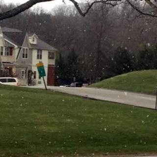 A suburban house with snow falling on a winter day.
