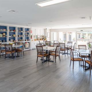 A bright and spacious dining area with tables, chairs, and bookshelves lining the walls.