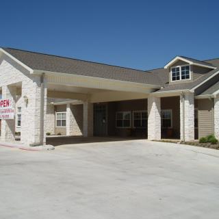 A modern residential building with a covered entrance and spacious driveway.